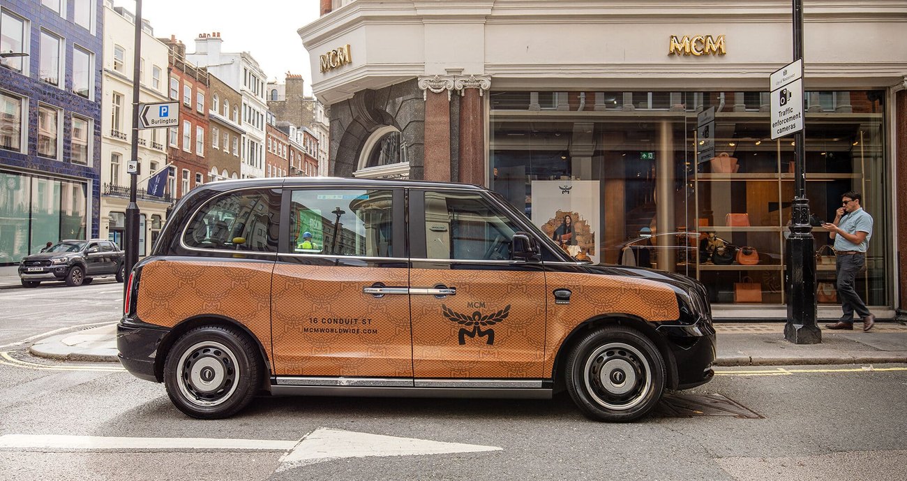 A London taxi carrying a superside advertising panel along the side of the vehicle