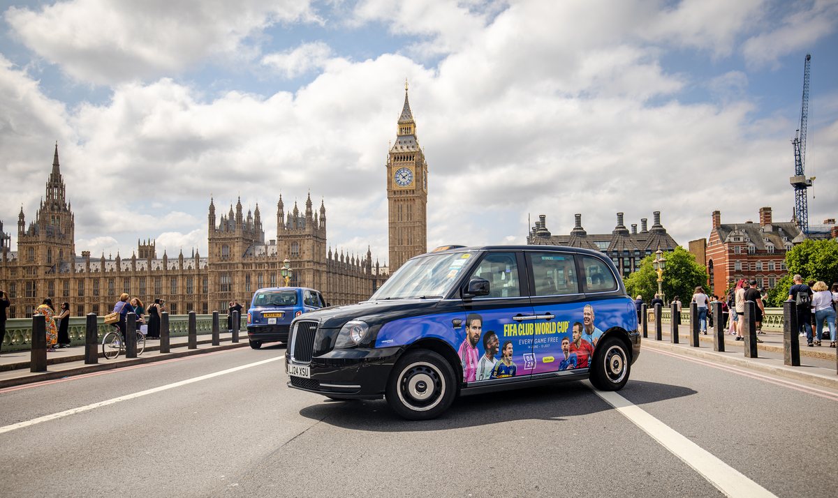 A London taxi in DAZN FIFA Club World Cup livery passing the Houses of Parliament
