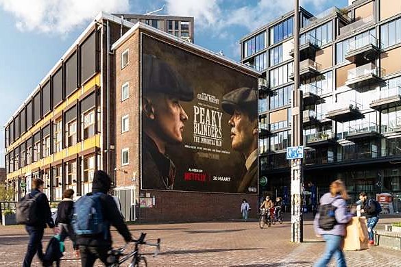 A large hand-painted advertisement covering the end wall of an apartment building above a public square