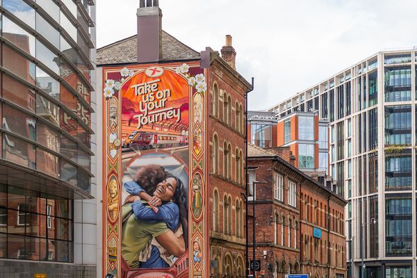 A tall painted gable end showing two people embracing, with display lettering above