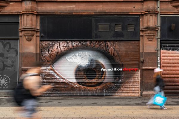 Shop shutters painted with a single large eye at street level