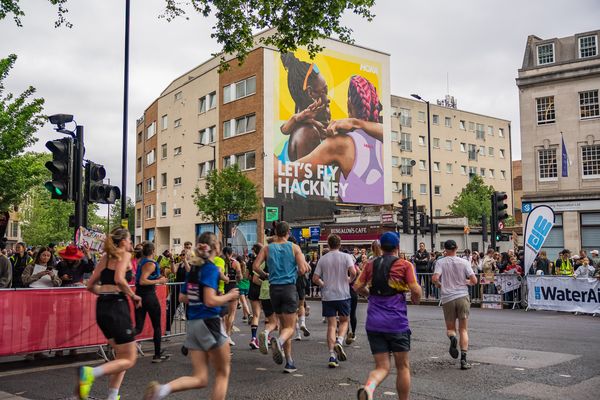 Runners passing a building end painted with a figure and large lettering