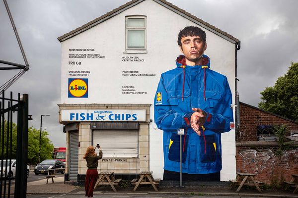 A gable end above a fish and chip shop painted with a figure in a blue coat