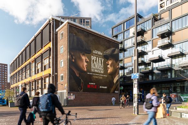 A tall brick gable end painted with two figures in flat caps for a television series