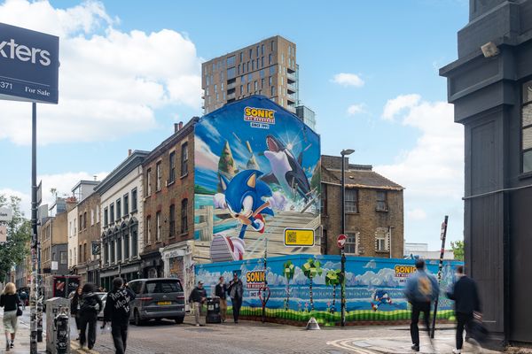 A building end and hoarding painted with a blue cartoon character and sky