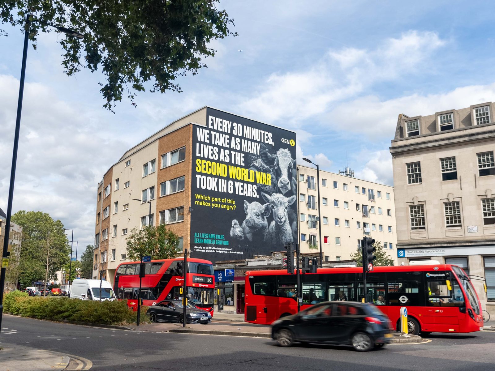 A hand-painted wall towering over two London buses on a main road