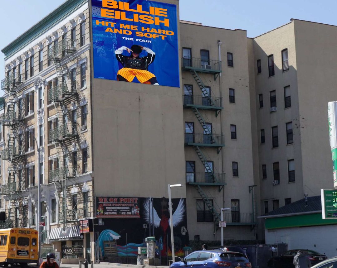 A large corner wall overlooking a busy Bushwick intersection, visible for several blocks
